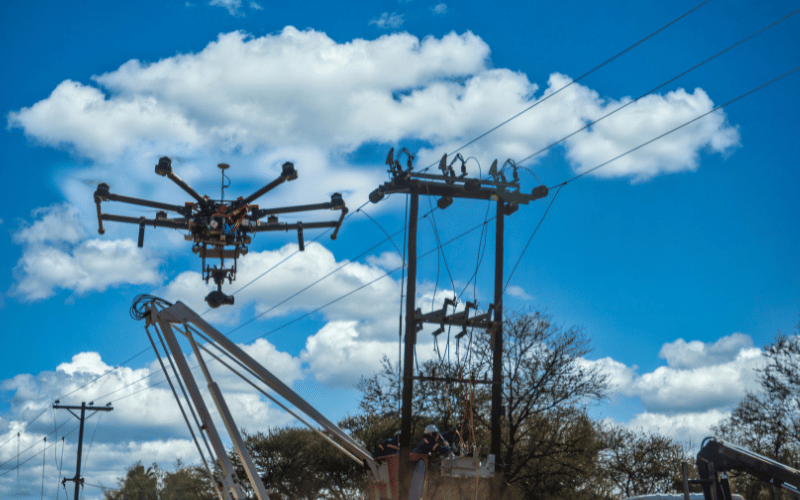 A drone inspecting electricity infrastructure while workers are fixing it