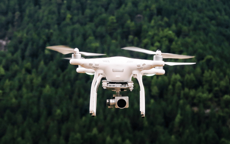 White drone floating above the forest